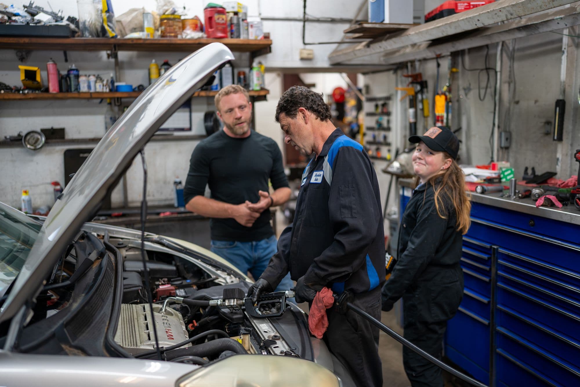 Absolute Auto Care technicians discussing a repair over an open engine bay